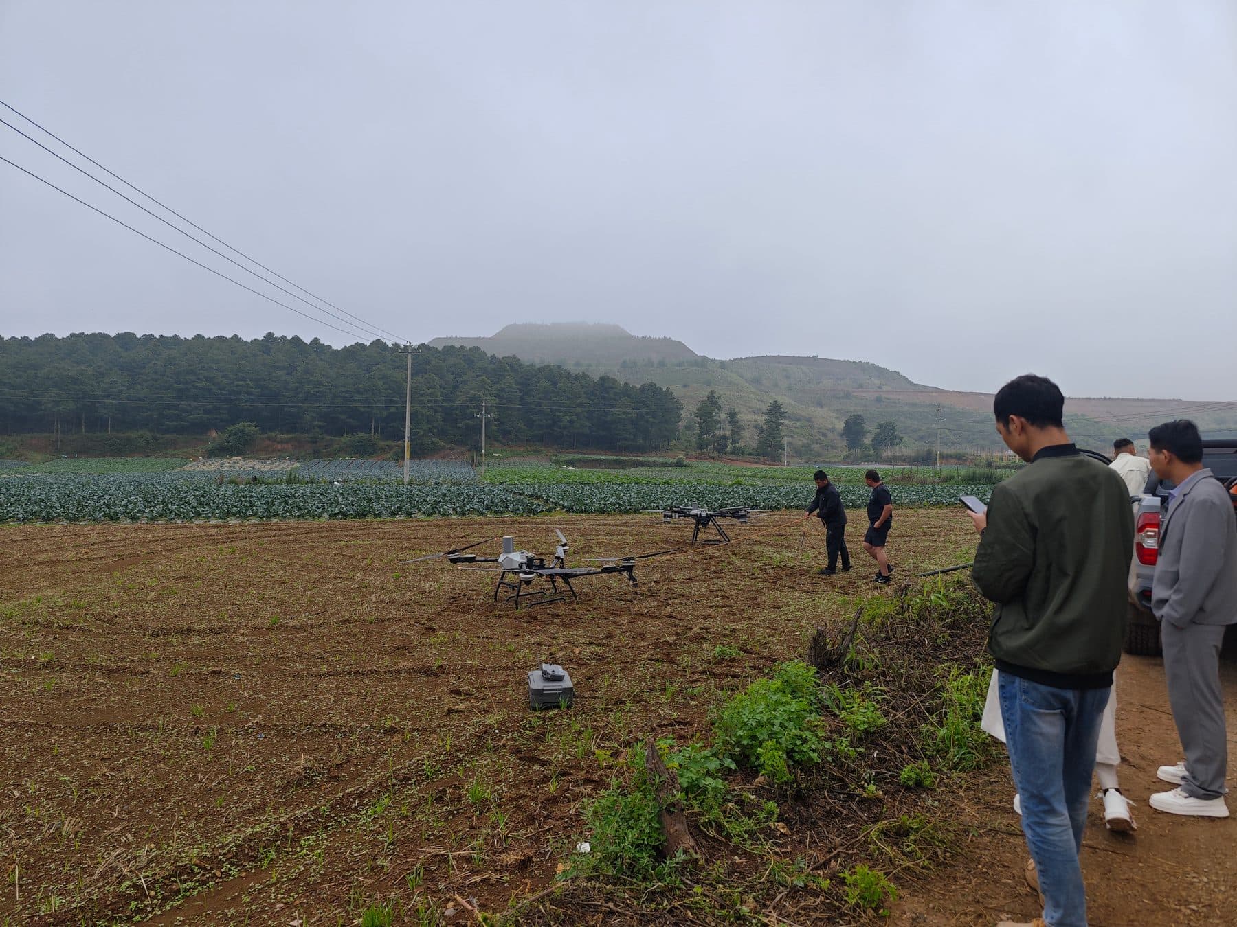 云南农业低空服务首飞现场,飞手与保障团队在田间进行无人机作业准备